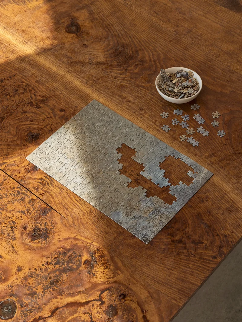 Puzzle à moitié assemblé sur une table en bois, pièces dans un bol