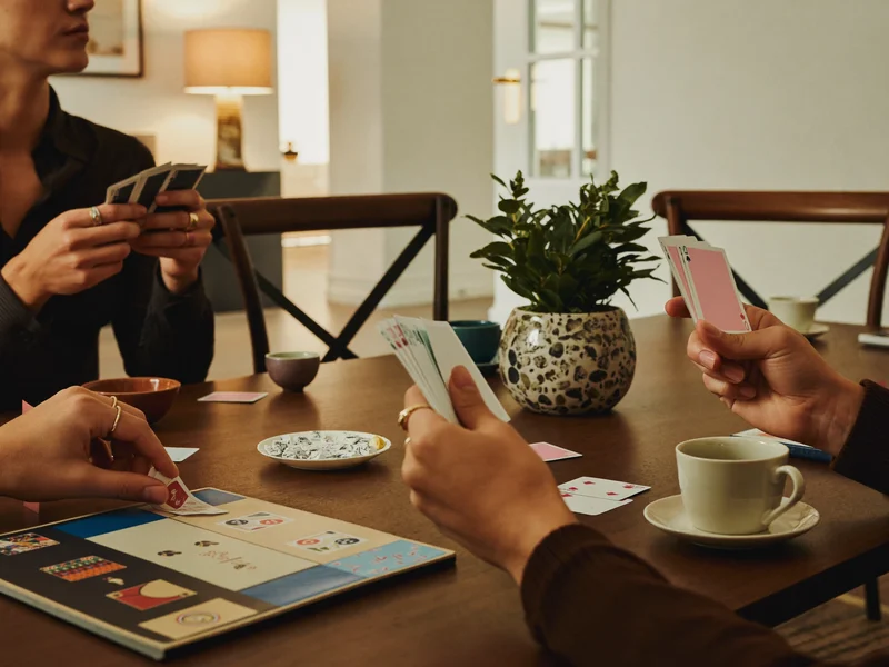 Mains autour d'une table pendant une soirée jeux, avec tasses de thé